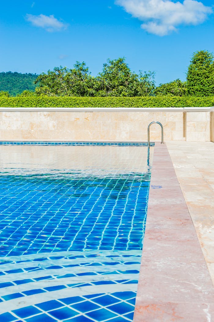 Home Bright and tranquil poolside scene, capturing a turquoise swimming pool under a clear blue sky.